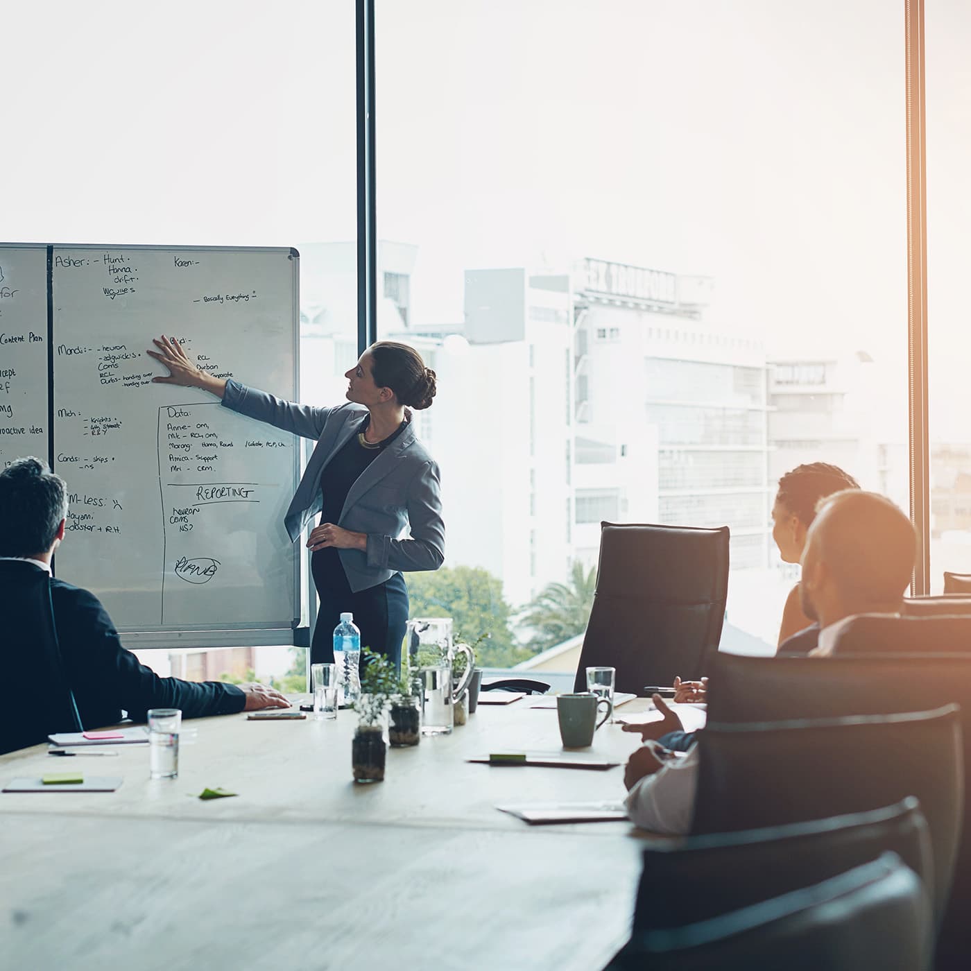 Business meeting with a woman at a whiteboard for fleet operations planning. Business meeting with a woman at a whiteboard for fleet operations planning.